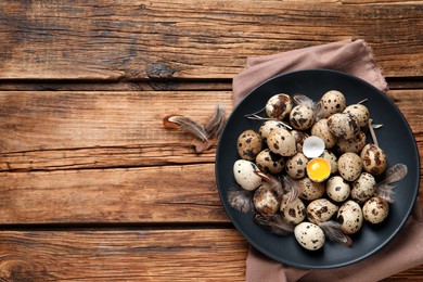 Plate with quail eggs on wooden table, top view. Space for text