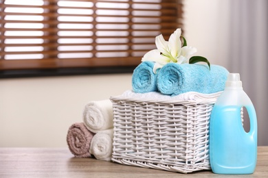 Basket with towels and detergent on table in room, space for text