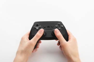 Young woman holding video game controller on white background, closeup