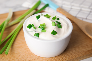 Fresh sour cream with onion on wooden board, closeup