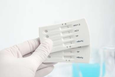 Doctor holding two disposable express tests for hepatitis indoors, closeup
