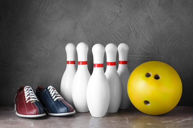 Bowling shoes, pins and ball on grey marble table