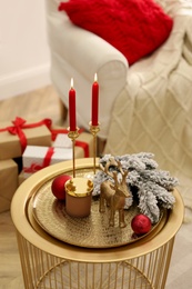 Christmas composition with decorative reindeer and candles on golden table in room