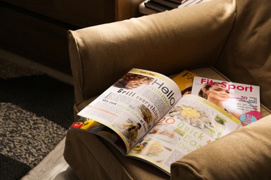 Different lifestyle magazines on comfortable armchair indoors