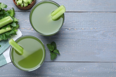 Photo of Celery juice and fresh ingredients on grey wooden table, flat lay. Space for text
