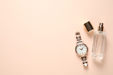 Luxury wrist watch and perfume on beige background, flat lay. Space for text