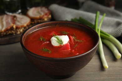 Clay bowl with Ukrainian borsch served on wooden table