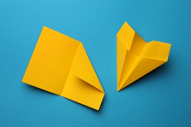 Handmade yellow plane and folded paper on light blue background, flat lay