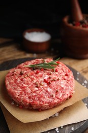 Raw hamburger patties with rosemary and spices on wooden board, closeup
