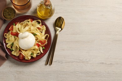 Plate of delicious pasta with burrata, peas and tomatoes served on white wooden table, flat lay. Space for text