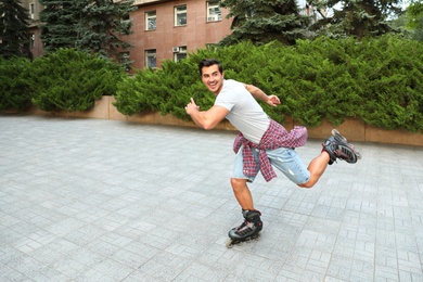 Photo of Handsome young man roller skating outdoors. Recreational activity