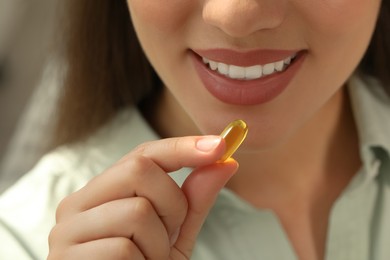 Young woman taking dietary supplement pill, closeup