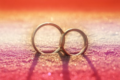 Double exposure of lesbian flag and wedding rings on sandy beach, closeup