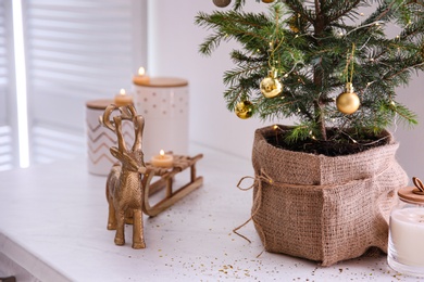 Small decorated Christmas tree and reindeer figure on countertop in kitchen, closeup