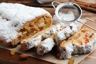 Traditional Christmas Stollen with icing sugar on wooden board, closeup