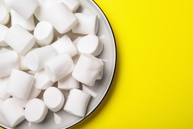 Delicious puffy marshmallows on yellow background, top view. Space for text