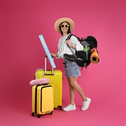 Female tourist with travel accessories on pink background