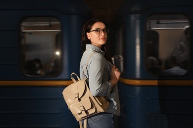 Photo of Beautiful woman with backpack in front of train on subway station. Public transport