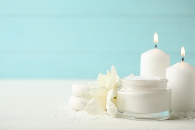 Spa composition with cream, candles and flowers on white table, space for text