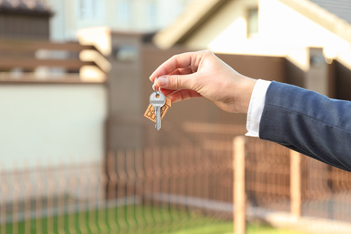 Real estate agent holding key outdoors, closeup