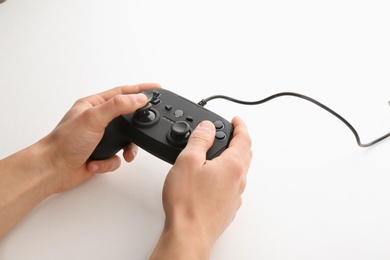 Young man holding video game controller on white background, closeup