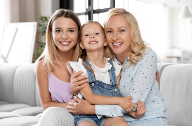 Young woman with mature mother and little daughter in living room