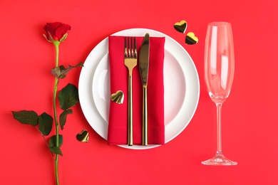 Beautiful table setting for romantic dinner on red background, flat lay. Valentine's day celebration