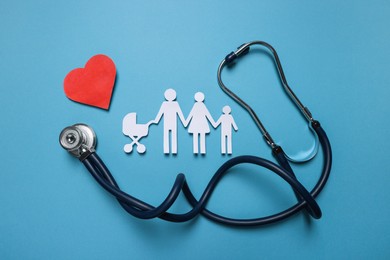 Paper family figures, red heart and stethoscope on light blue background, flat lay. Insurance concept