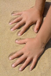 Child leaving handprints on sand outdoors, closeup. Fleeting time concept