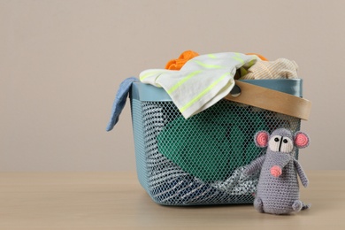 Laundry basket with different children's clothes and toy on wooden table. Space for text