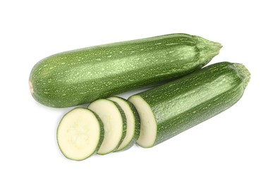 Whole and cut ripe zucchinis on white background, top view