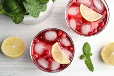 Tasty refreshing cranberry cocktails with lemon on white wooden table, flat lay