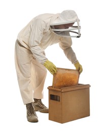 Beekeeper in uniform taking frame with honeycomb out of wooden hive on white background