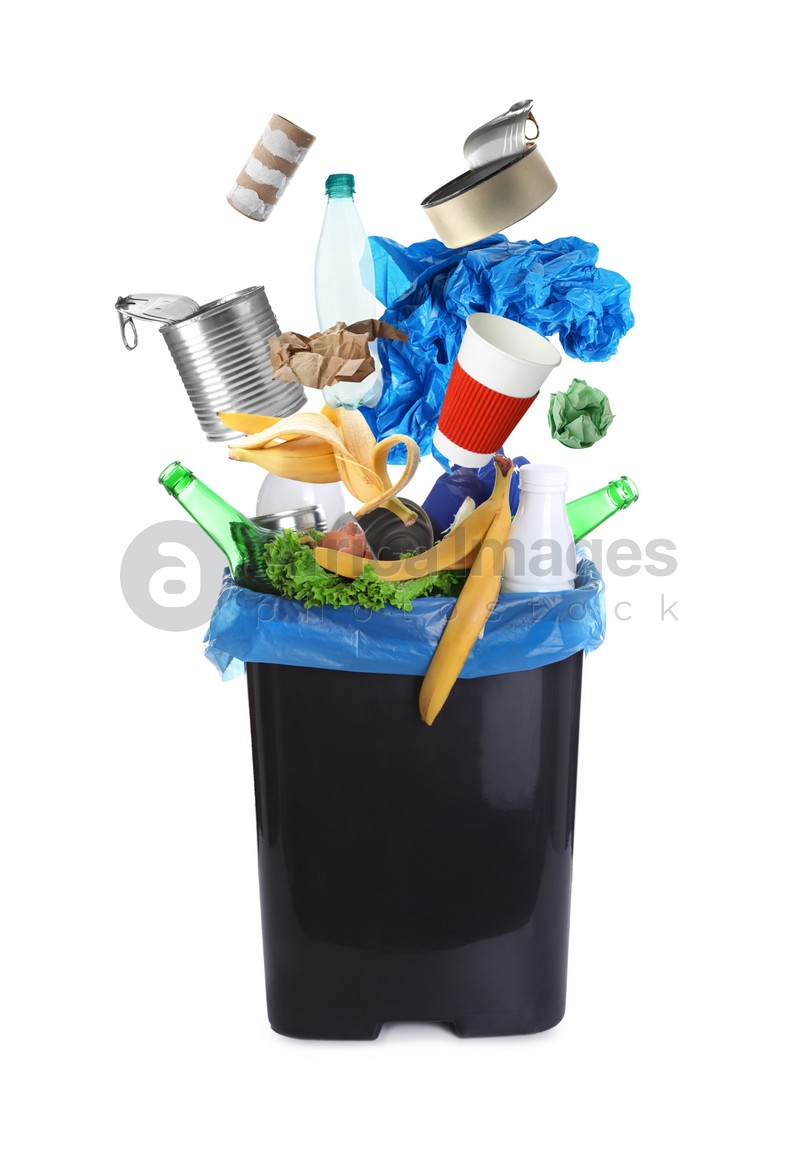 Different garbage falling into trash bin with rubbish bag on white background