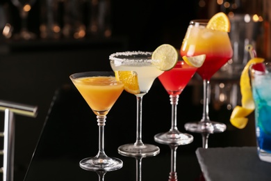 Photo of Different delicious cocktails on black table in bar