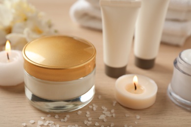 Composition with skin care products and candles on wooden table, closeup