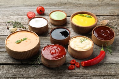Many bowls with different sauces on wooden table