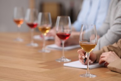 Sommeliers making notes during wine tasting at table indoors, closeup