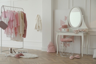 Dressing room interior with clothing rack and round mirror