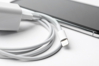Photo of Smartphone and charging cable with adapter on white background, closeup