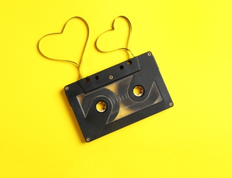 Music cassette and hearts made with tape on yellow background, top view. Listening love song