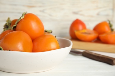 Delicious fresh persimmons on white table, closeup