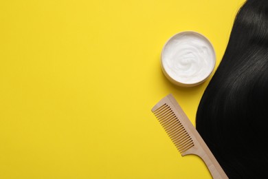 Lock of healthy black hair, cosmetic product and comb on yellow background, flat lay. Space for text