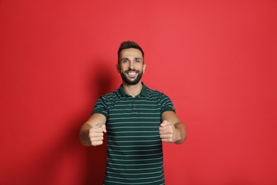 Happy man pretending to drive car on red background
