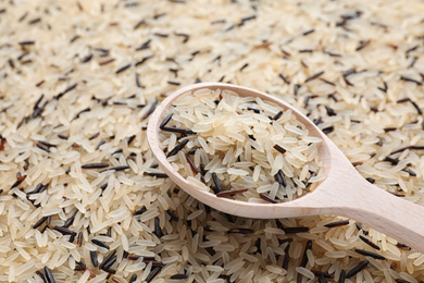 Mix of brown and polished rice with wooden spoon, closeup