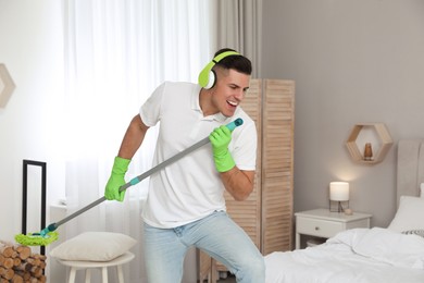 Man with mop singing while cleaning in bedroom