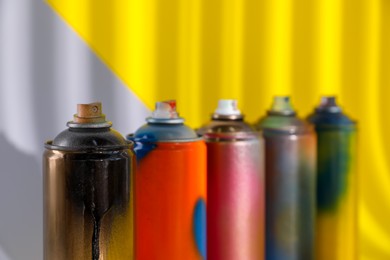Photo of Used cans of spray paints on color background, closeup