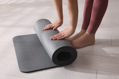 Woman unrolling yoga mat at home, closeup