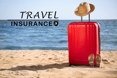 red suitcase, hat and flip flops on sand near sea. Travel insurance