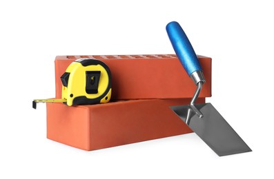 Photo of Red bricks, tape measure and trowel on white background